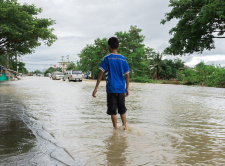 SAKON NAKHON, THAILAND - JULY 29, 2017 : Boy walking with water floodedのeditorial素材