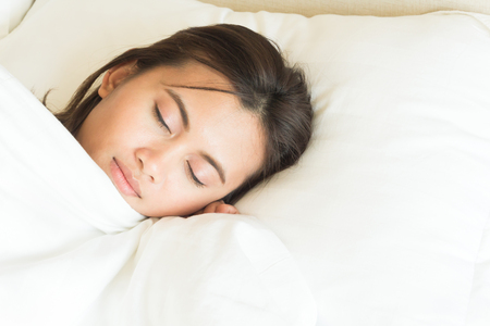 Closeup young woman sleeping with happy face in the bed, copy spaceの写真素材