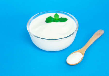 Close up yogurt  in glass bowl  with wooden spoon on blue backgroundの写真素材