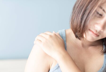Closeup woman hand holding shoulder with pain on white backgroundの写真素材