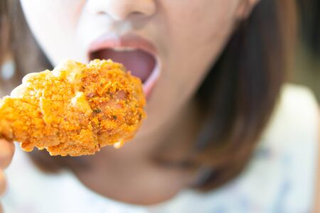 Close up woman eating fried chicken legs, selective focusの写真素材