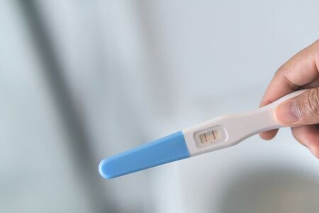 Closeup woman hand holding pregnancy test in bathroom, health care concept, selective focusの写真素材