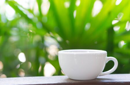 Closeup hot americano coffee on glass table with green nature backgroundの写真素材