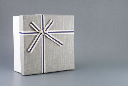 Grey gift box with ribbon on grey background, copy spaceの写真素材