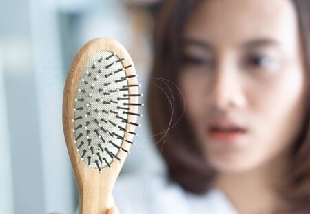 Woman hand holding comb with serious hair loss problem for health care shampoo and beauty product concept, selective focusの写真素材