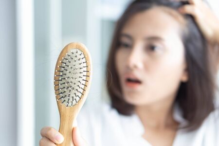 Woman hand holding comb with serious hair loss problem for health care shampoo and beauty product concept, selective focusの写真素材