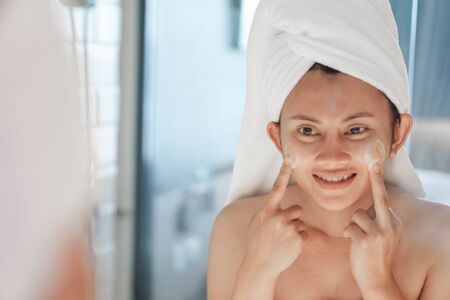 Close up woman looking for washing face in the mirror with smiling after bath, health care and beautyの写真素材