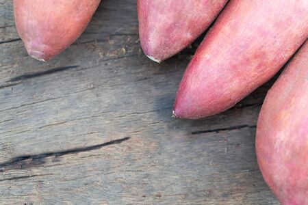 Raw sweet potato on wood table, healthy food concept