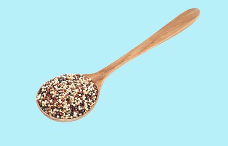 Quinoa in wooden spoon isolated on blue background, health care conceptの写真素材