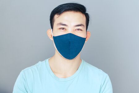 Closeup asian man wearing face mask for protect air polution or virus covid 19 with grey background, health care and medical conceptの写真素材