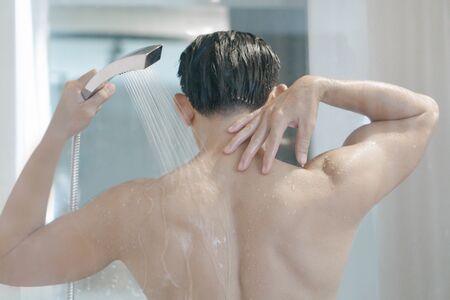 Closeup young man washing hair with with shampoo in the bathroom, vintage tone, selective focusの写真素材