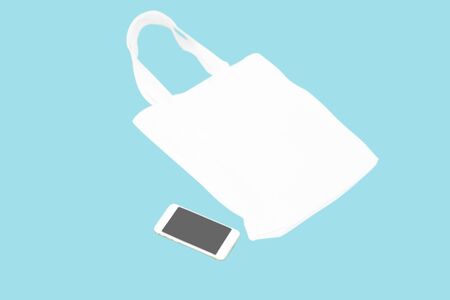 Closeup white bag canvas fabric with smartphone isolated on blue background, Save the world conceptの写真素材