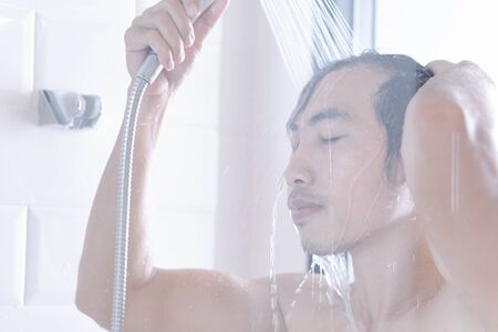 Closeup young man washing hair with with shampoo isolated on whiteの写真素材