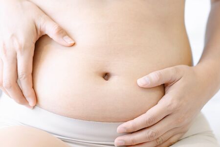 Pregnancy woman on white bed background, health care and medical concept,Young woman expecting a babyの写真素材