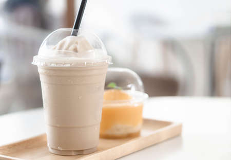 Close up glass of ice americano coffee and orange cake on wood table, selective focusの写真素材