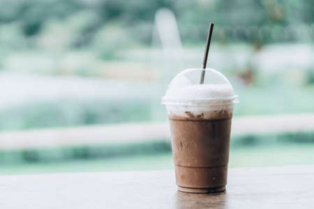 Close up glass of ice chocolate on wood table, selective focus