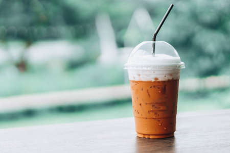 Closeup thai milk tea on wood table with nature backgroundの写真素材