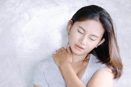 Closeup woman holding neck with pain, healthy care and medical conceptの写真素材