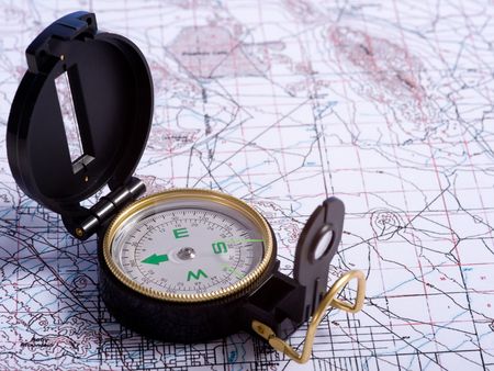 A black engineer's compass lying on top of a topographical map
