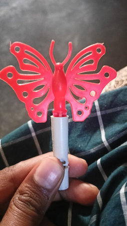 A closeup shot of a person holding a red butterfly shaped candleの写真素材