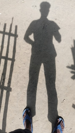 Shadow of a man standing on the concrete floor with shadow of a fenceの写真素材