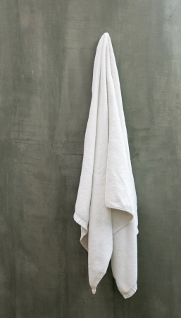 Hanging White Towel draped on Exposive Concrete Wall in the Bathroomの写真素材