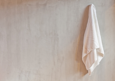 Hanging White Towel draped on Exposed Concrete Wall in the Bathroomの写真素材