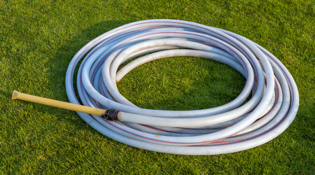 Round pattern rubber band on green grass field for watering plant in the gardenの写真素材