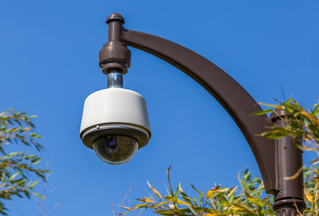 Security camera, CCTV hangs in park for monitoring with the blue sky background