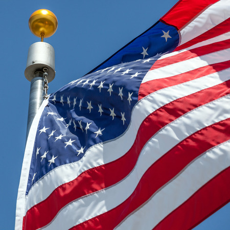 Close-up American flag blows in the wind with flag pole, focus on star of waving flag