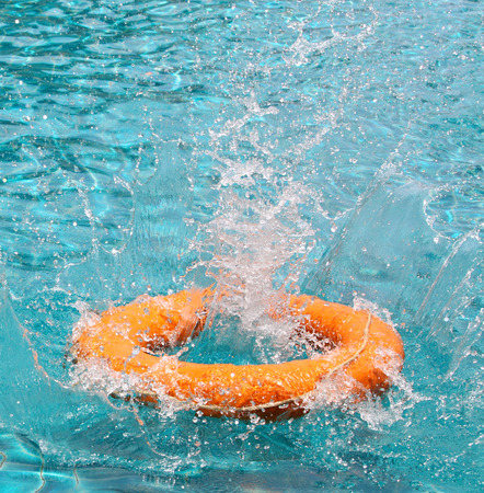 Orange life buoy is thrown to clear water swimming pool, for the emergency caseの写真素材