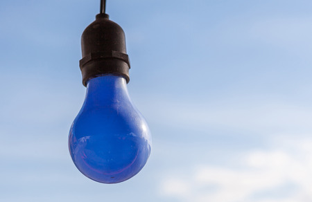 Hanging blue light bulb with blue sky backgroundの写真素材