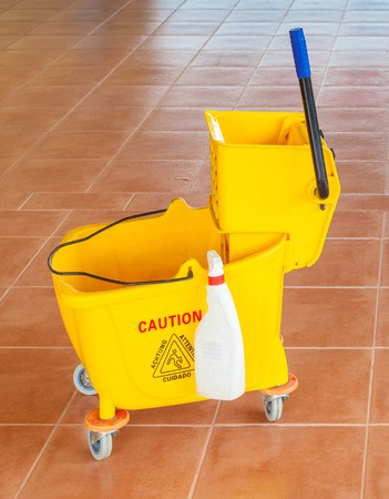 Yellow mop bucket and wringer with caution sign on the floor in office building, for cleaningの写真素材