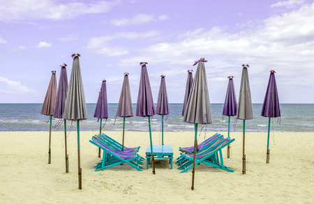 Beach chairs around with closed sun umbrellas on the white sand beachの写真素材