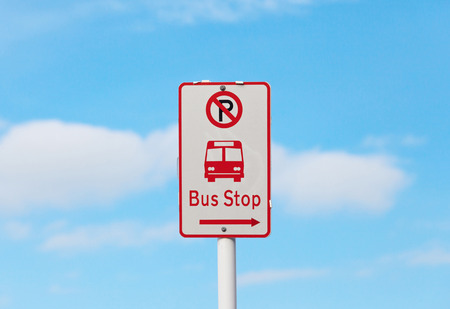 The bus stop and no parking sign with blurry blue sky background.の写真素材