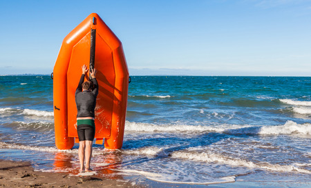 The young man lifeguard is pushing rescue rubber boat on the sea, concept of security on beach.