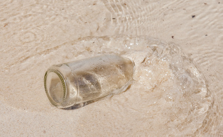 The glass bottle sinks into water and beach sandの写真素材