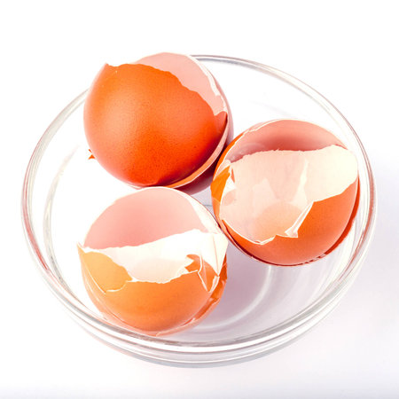 After cooking, broken eggshell in white bowl on white background.