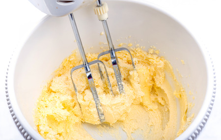 Eggs, sugar and butter cream in the mixing bowl process of homemade bakery.の写真素材
