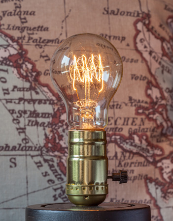 Classic edison light bulb with looping carbon filament on map background.の写真素材
