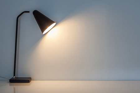The modern desk lamp illuminate on the wall background. (left the right space for text)の写真素材
