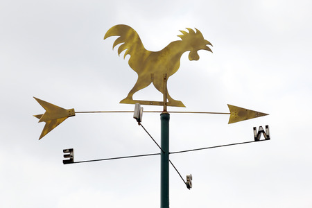 The golden metal weathervane over the white sky background.