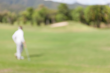 Blurred photo of golf player on green during golf match.の写真素材