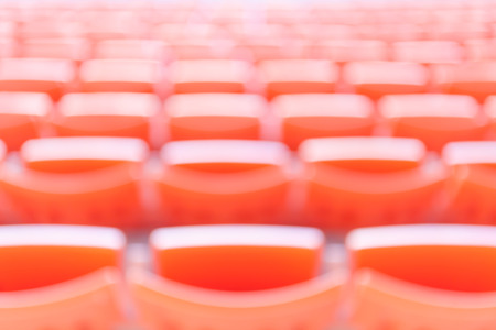 Abstract blurred background of empty red stadium chairs in a row.
