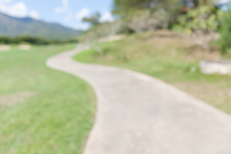Blurred photo of pathway curving through green lawn in golf course.の写真素材