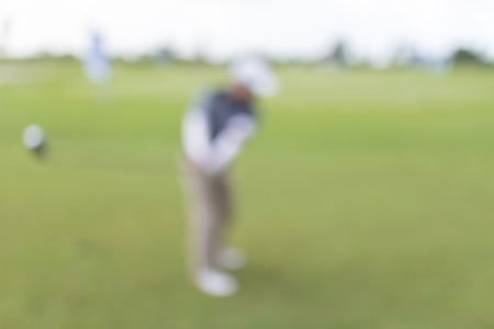 Blurred photo of golf player on green during golf match.の写真素材