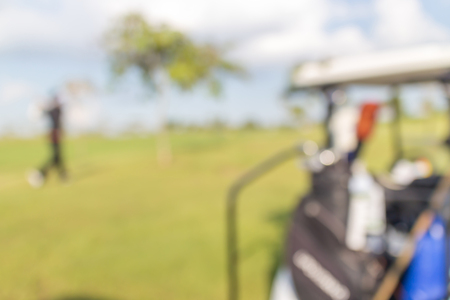 Blurred photo of golfer and golf cart in green golf course.の写真素材