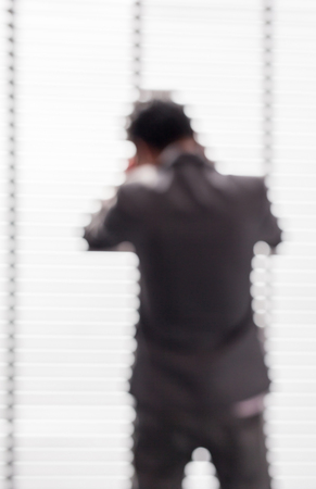 Blurred picture of business man using phone near the window in office building.の写真素材