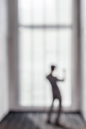 Blurred business man stands near the window in office building feel happy with his goal achievement.の写真素材
