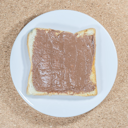 Toast with chocolate spread on white plate on wooden plate background.の写真素材